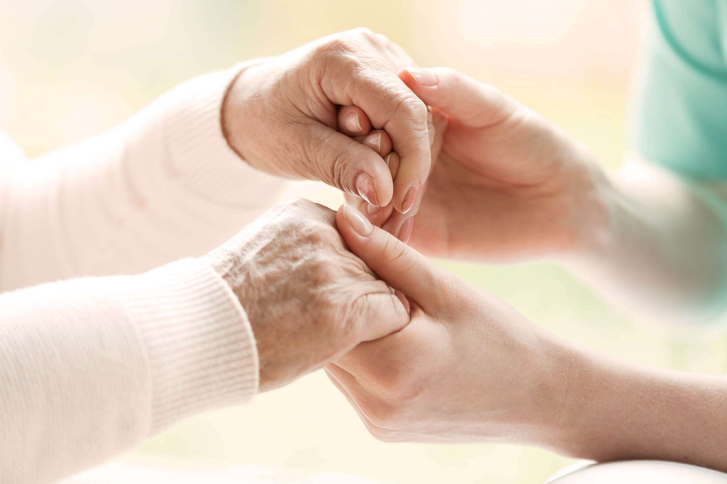 Closeup of hands of young granddaughter holding hands of her gra